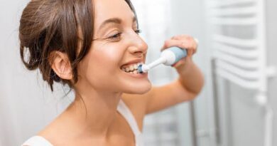 Escovas de dentes elétricas Oral-B e Philips alinhadas sobre uma bancada de banheiro moderna.