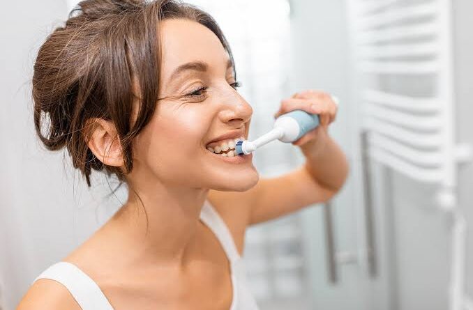 Escovas de dentes elétricas Oral-B e Philips alinhadas sobre uma bancada de banheiro moderna.
