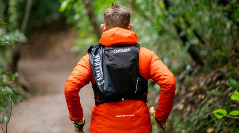 Corredor utilizando mochila de hidratação durante treino em trilha